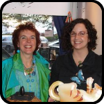 Two Women - One Holding a Lamp Made of Popsicles, The Other a Metal Cat Thing