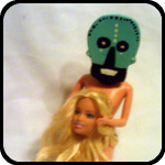 A Ceramic Skull About to Dine on a Barbie Doll Head A Ceramic Skull About to Dine on a Barbie Doll Head