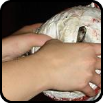Brit and Rosalie punching a hole in a paper mache hedgehog